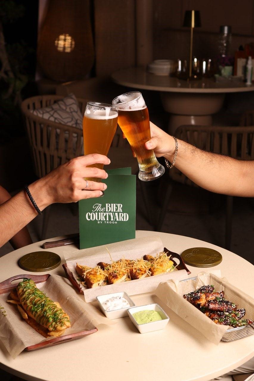 Friends toasting craft beer over shared plates at TBC, Pune